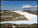 Am Monte Altissimo auf über 2000 m mit Blick hinüber zur Kapelle und einem Biker im Schneefeld, der sicher schon nasse Füße hat