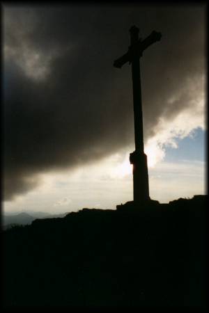 Das Gipfelkreuz der Rotwand im spätabendlichen Gegenlicht